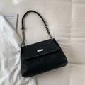 Detail of a black suede handbag with metallic buckle and silver chain on white fabric - Black without Pendant