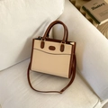 Detail of two-tone beige and brown tote bag on sofa with golden hardware and PU leather - Khaki