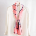 Elegante foulard di seta rosa con fiori e strisce blu annodato su una camicia bianca - Rosa