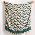 Detail view of woven plaid scarf with multi-color grid patterns and colorful fringe tassels - Green