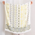 Close-up of bohemian linen shawl featuring gold-stamped paisley and tassel fringe - Yellow