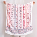 Close-up of bohemian linen scarf with colorful paisley patterns and fringe details - Red