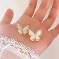 Detail of gold butterfly stud earrings with white shell and zircon held in hand - White Butterfly (Gold)