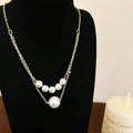 Dettaglio di un'elegante collana a due strati dorata con perle su supporto nero - Oro