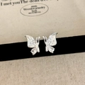 Macro detail of silver butterfly studs with cubic zirconia drop on black velvet - Silver Butterfly Stud Earrings