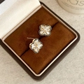 Detailed macro view of gold four-leaf flower stud earrings with zircon inlay in a velvet box - Four Petal Flower / Gold