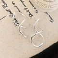 Close-up of silver spiral geometric earrings on artistic fabric with a candle background - Silver