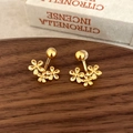 Detail of gold flower stud earrings arranged in a curved daisy pattern on a wooden tray - Gold