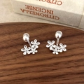 Detailed view of silver flower stud earrings on dark wood tray with white gift box - Silver