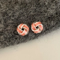 Detail of silver twisted knot earrings with coral pink enamel inlay and rope texture - Red