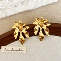 Vue détaillée de boucles d'oreilles fleurs dorées irrégulières avec texture de métal martelé - Doré