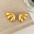 Close-up of golden teardrop fan-shaped stud earrings on a textured beige fabric background - Gold