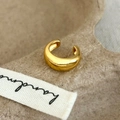 Detailansicht eines polierten goldenen C-förmigen Ear Cuff auf handgemachtem Hintergrund - C-Förmige Ohrmanschette / Gold