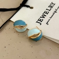 Detalle de pendientes de esmalte azul y dorado con diseño aerodinámico de estilo retro - Pendientes de Botón Azules