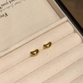 Detalle macro de pendientes de botón de frijol de oro pulido en joyero de terciopelo - Dorado