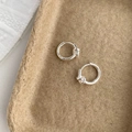 Macro-opname van zilveren knoopoorbellen op bruine achtergrond met metalen details - Zilver