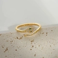 Macro detail van gouden slangenring met groene edelsteenogen en sprankelende zirkonia - Gouden slangenring