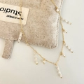 Dettaglio collana a nappa dorata con perle e perline sfaccettate su lino - Collana con Nappine in Perle Bianche Lucide