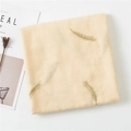 Detailstruktur eines Baumwoll-Leinen-Schals mit goldener Federstickerei auf Beige - Beige
