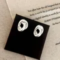 Dettaglio dei piccoli orecchini a lobo intrecciati in argento con zircone centrale lucido - Stile Nodo Incrociato con Zirconia (A-458)