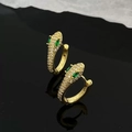 Makro-Detail goldener Schlangenohrringe mit weißen Zirkonia und grünen Edelsteinaugen - Schlange Zirkonia Ohrringe / Gold