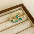 Macro view of gold flower earrings with blue enamel petals and sparkling zircon center - Blue