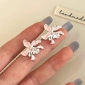 Close-up of pink enamel orchid earrings with teardrop zircon on silver metal - Pink