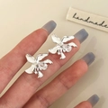 Close-up of handmade flower stud earrings with pear-cut zircon and silver petals - White