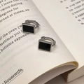 Dettaglio di orecchini rettangolari in argento con intarsio nero su un libro - Chiusura a Cerchio Argentata con Piastra Nera