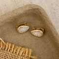 Détail de boucles d'oreilles goutte dorées serties de zircons sur support en papier - Doré
