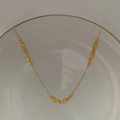 Detalle de un collar de cadena de varias capas chapado en oro sobre un plato de cerámica gris - Dorado