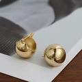 Detailansicht goldener Kugelohrringe auf einem minimalistischen Display für Damen - Goldene Kugel-Ohrstecker