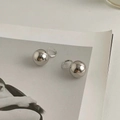 Detalle macro de pendientes de bola de plata pulida sobre una revista de arte mínima - Colgante de Bola Plateada (A-559) / Plateado