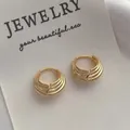 Dettaglio macro di orecchini a cerchio dorati con design a coste multistrato su cartoncino - Orecchini a Cerchio Geometrici / Oro