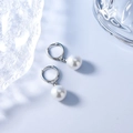 Eleganti orecchini a cerchio con perle in argento S925 su sfondo blu minimalista - Orecchini Pendenti con Perla di Conchiglia Argentata