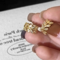 Detailopname van de vergulde bladoorbellen met glinsterende witte zirkonia steentjes - Gouden Blad Zirkonia Oorbellen / Goud