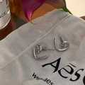 Macro view of silver heart earrings with irregular twisted design on a textured background - Silver