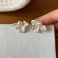 Macro di orecchini a fiore in argento martellato con perla centrale in mano - Argento