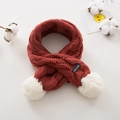 Red knit kids scarf with white pom-poms and hand-made label on soft cream background - Burgundy