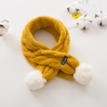Detail of yellow chunky knit scarf with white faux fur pom-poms and hand made label - Turmeric