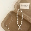 Close-up of shell fishtail pendant necklace with white pearls on a minimalist tray - White Fishtail Pearl Necklace
