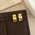 Dettaglio macro degli orecchini a C dorati geometrici con finitura lucida su velluto - Oro