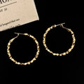 Primo piano dettagliato di orecchini a cerchio dorati con texture sfaccettata - 4cm Oro