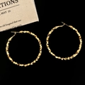 Macro detail of large gold-plated hoop earrings featuring a faceted hammered texture finish - 5cm Gold