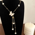Elegante gouden vlinderketting met zoetwaterparels en kwastjes op een zwarte displaystand - Vlinder Zoetwaterparel Kwastje Ketting