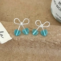 Détail de boucles d'oreilles nœud avec breloques cerise cœur bleu clair sur tissu texturé - Boucles d'Oreilles Clous Nœud Papillon Bleu