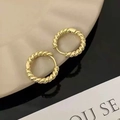 Macro-opname van minimalistische goudkleurige oorringen met gedraaide touwstructuur - Goud