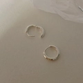 Primer plano de pendientes de aro geométricos en plata sobre una superficie gris - Plateado