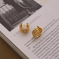 Detailansicht der goldfarbenen Lavatextur-Ohrringe auf einer Vintage-Kunstzeitschrift - Gold
