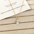 Dettaglio macro dell'elegante ciondolo in zircone a goccia su una sottile catena dorata - Collana di Zirconi a Goccia d'Acqua / Oro